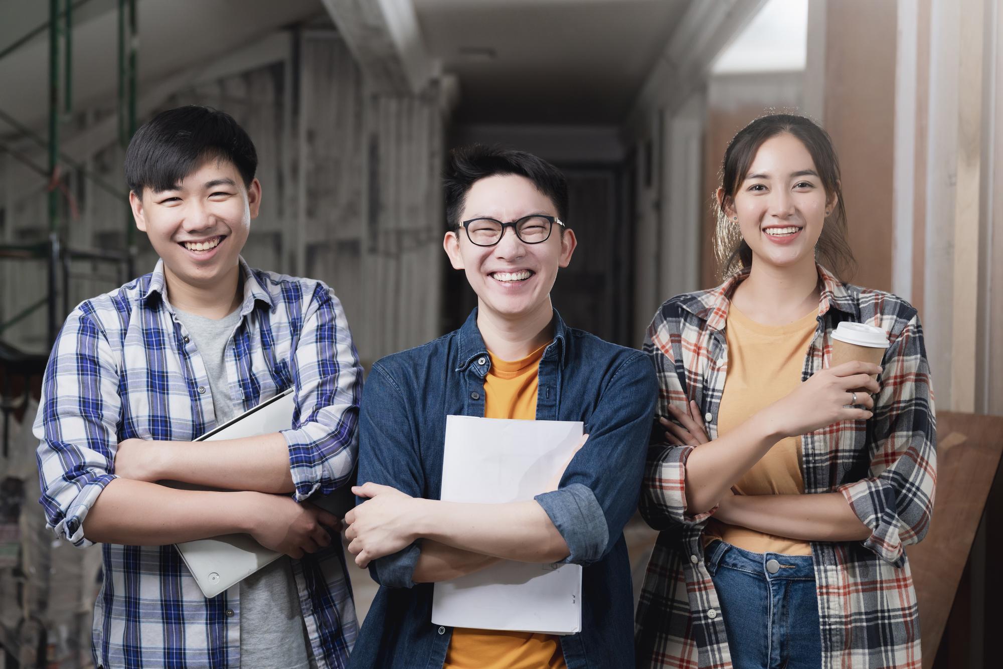 smiling-asian-teamwork-yound-interior-dreative-designer-portrait-stand-together-hand-chest-confident-smart-team-with-background-construction-home-renovate